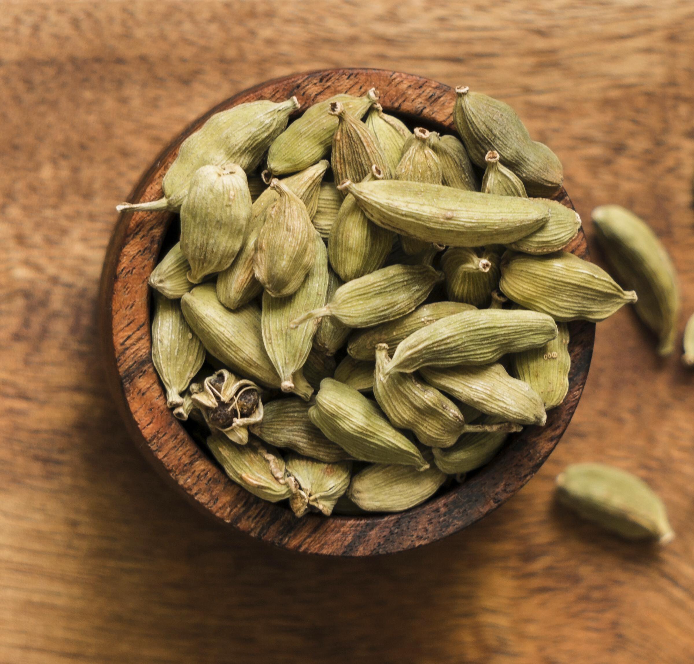 Abundant collection of premium whole green cardamom pods arranged together showcasing their natural pale to deep green coloring and distinctive longitudinal ridged patterns characteristic of high-quality spice specimens